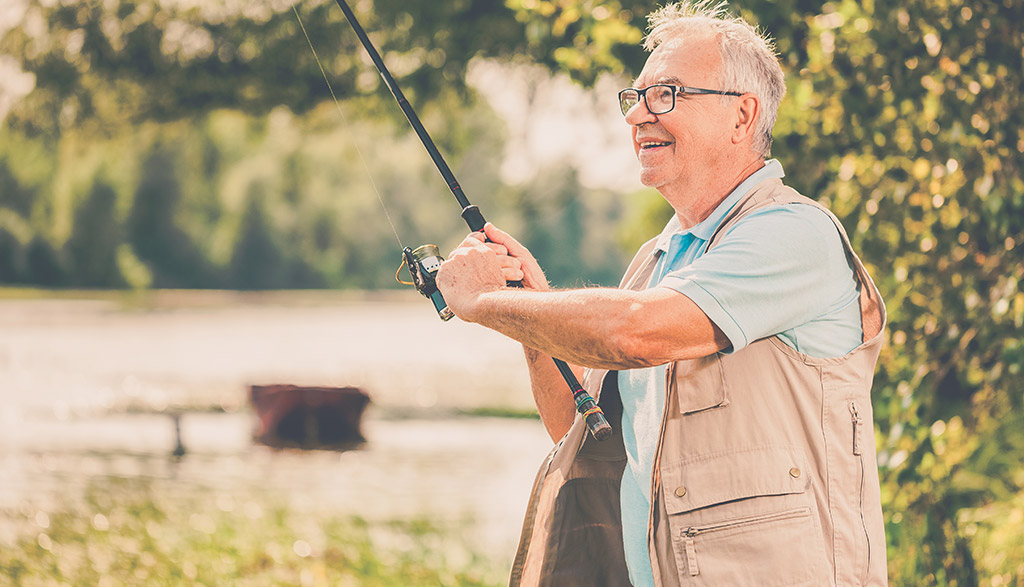 elderly man fishing on the bank of a river