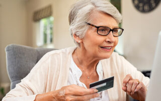 Senior woman holding credit card while online shopping
