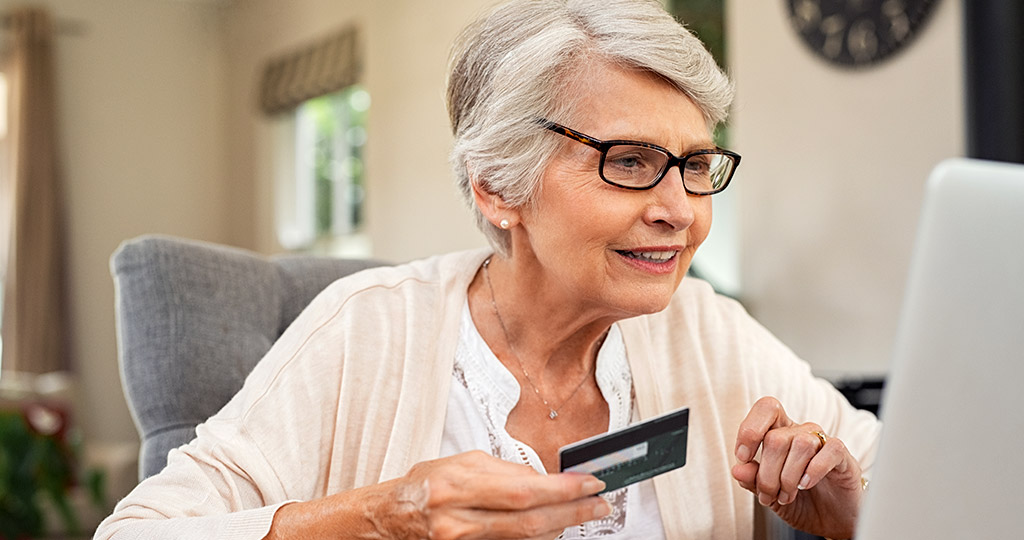 Senior woman holding credit card while online shopping