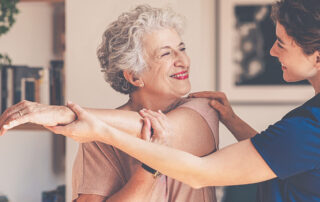 Caregiver helping senior woman stretch her arm across her body