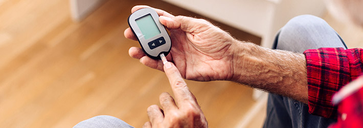 Senior man checking blood sugar levels using blood glucose meter