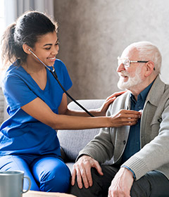 Female physician using stethoscope to listen to heart of senior man