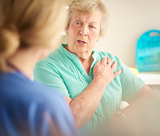 Senior woman talking with nurse about heart health