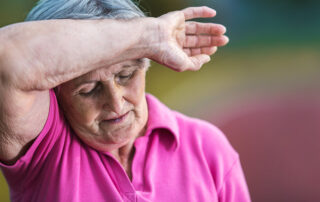 Elderly woman holding back of wrist against forehead due to heat