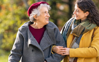 Smiling senior woman walking outside with caregiver