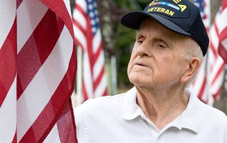 Senior veteran wearing Korea War hat looking at American flag