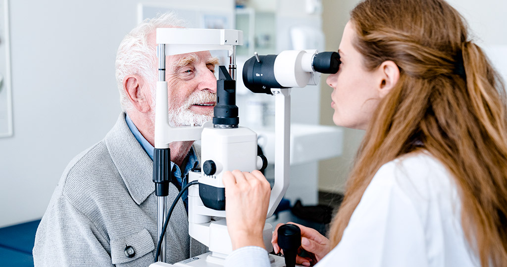 Elderly man getting vision and eyes checked by female ophthalmologist