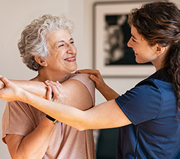 Caregiver helping senior woman practice in-home exercises