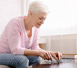 Elderly woman putting together a puzzle as one of her hobbies