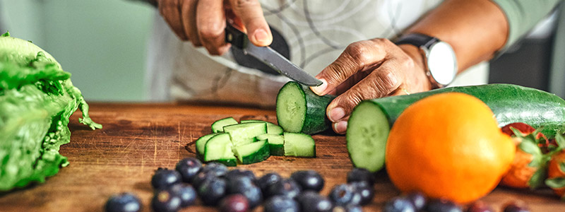 Person preparing nutritious meal while cutting produce