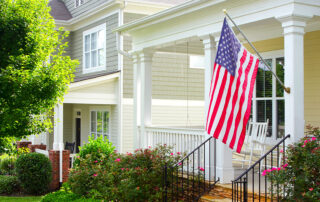American flag hanging on the porch of a quaint bungalow home