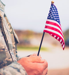 Veteran holding American flag while in uniform